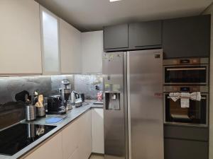 a kitchen with white cabinets and a stainless steel refrigerator at Casa dos sonhos em Vale do Lobo in Loulé