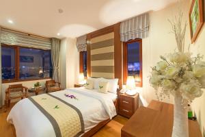 a hotel room with a bed and a vase of flowers at Moonlight Hotel & Apartment - High Floor, panoramic views of the city and river, Dragon Bridge in Da Nang