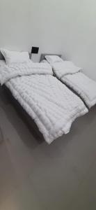 Saran Homestay في آغْرا: سرير عليه ملاءات ووسائد بيضاء