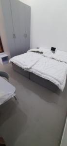 Saran Homestay في آغْرا: سرير أبيض في غرفة ذات أرضية بيضاء