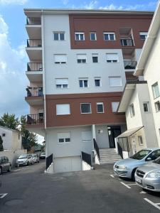 a large apartment building with cars parked in a parking lot at Apartment Sanja in Belgrade