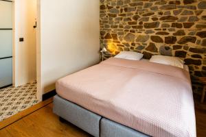 a bed in a room with a stone wall at Villa Basse Cour in Durbuy