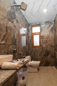 een badkamer met een toilet, een wastafel en een spiegel bij Mary Chalet shanag manali near nehru kund 4 km from mall road in Rahla