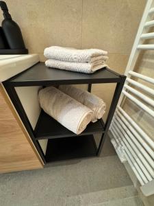 a black shelf with towels on it in a bathroom at LakeCity Apartment in Klagenfurt