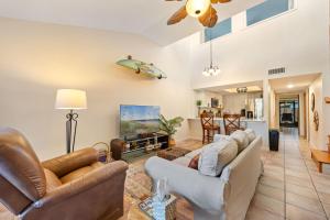 a living room with couches and a surfboard on the wall at Beach Townhome Steps from Downtown Cocoa Beach in Cocoa Beach