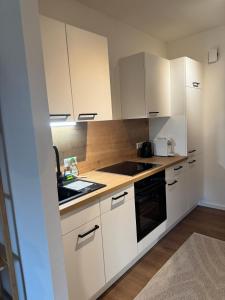 a kitchen with white cabinets and a stove top oven at LakeCity Apartment in Klagenfurt
