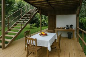 a table and chairs on a deck with a staircase at Camelliana Horizon Pongyang - Nature Retreat in Mae Rim