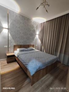 een slaapkamer met een bed met een blauw dekbed bij Tandau apartment in Taldykolʼ