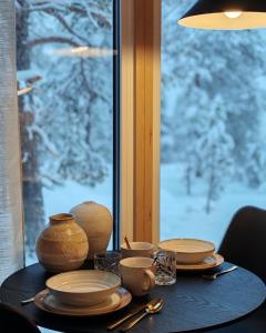 Villa Louhikko - Aavasaksa, Lapland في Aavasaksa: طاولة عليها أوعية وأدوات مائدة، موضوعة على طاولة بها نافذة. +5 صور