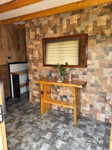 a stone wall with a wooden table in a room at Cabañas El Quincho de Putú in Constitución