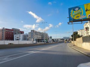 an empty street in a city with buildings and a billboard at Dar Mima in Tunis
