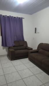 a living room with two brown couches and a blue curtain at Casa em Ubatuba beach two in Ubatuba