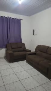 a living room with two brown couches and a blue curtain at Casa em Ubatuba beach two in Ubatuba