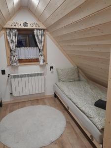 a small room with a bed and a rug at Domek GAWRA in Ząb
