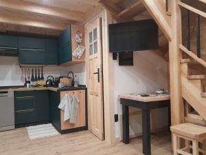 a kitchen with green cabinets and a wooden floor at Domek GAWRA in Ząb