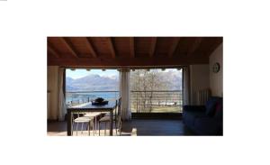 Una sala de estar con una mesa y sillas y una gran ventana. en Rustico Prato Grande con vista lago, en Carriola