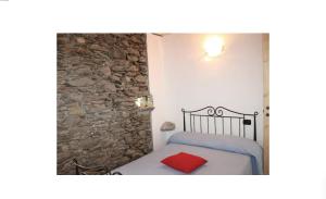 a bedroom with a bed and a stone wall at Rustico Prato Grande con vista lago in Carriola