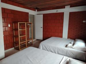 a room with two beds and a brick wall at Leño Verde in Espinal