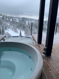 Ecottage котедж для двох у горах із чаном-джакузі في سلافسكي: حوض جاكوزي مع إطلالة على حقل مغطى بالثلوج