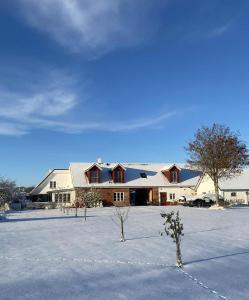 a large white barn with two trees in the snow at Annagården Österlen in Kivik