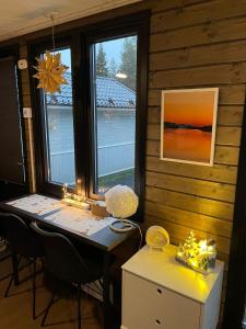 a room with a table and two windows with lights at Santa's little cottage in Rovaniemi