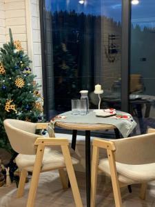 Ecottage котедж для двох у горах із чаном-джакузі في سلافسكي: طاولة وكرسيين وشجرة عيد الميلاد