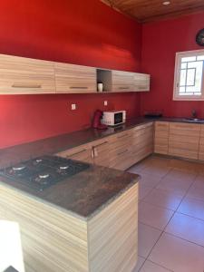 una cucina con pareti rosse e piano cottura forno superiore di Villa en face de pain de sucre  1 altra foto
