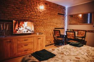a bedroom with a brick wall and a bed and a tv at Apartament Hallera in Chełmno