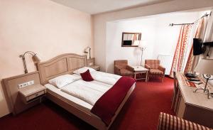 Habitación de hotel con cama con alfombra roja en Hotel Garni Pension zur Wacht, en Strobl