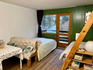 a bedroom with a bed and a couch and a window at Studio près du lac in Malbuisson