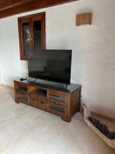 een houten entertainmentcentrum met een flatscreen-tv bij Ohana Villa Paula in Huertas del Palmar