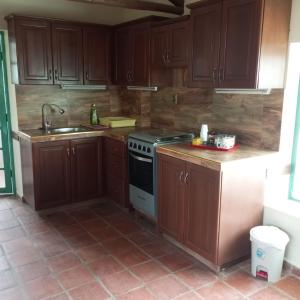 een keuken met houten kasten, een fornuis en een wastafel bij Mya Esencia Espacio Eco Turístico Camping in Tinquipaya