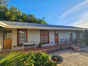 Stylish Cozy Stay at Ferndale House Apartments في بورت ألفريد: منزل مع مقعد على الفناء