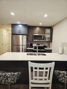 a kitchen with a sink and a counter with chairs at Livingston Calgary Lovely space in YYC