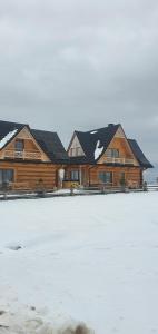 a large log house with snow in front of it at Bachledowy Wierch 2 in Czerwienne