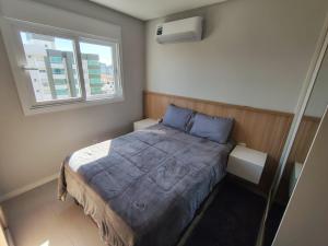 a small bedroom with a bed and a window at Praia e mar in Tramandaí