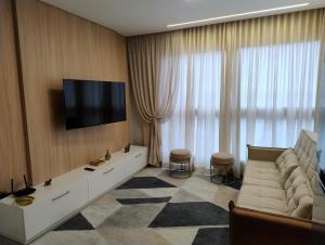 a living room with a couch and a flat screen tv at Praia e mar in Tramandaí