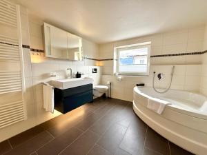 a bathroom with a tub and a sink and a toilet at Ferienhaus Alpenlodge in Oberstdorf +47 photos