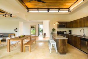 an open kitchen and dining room with a wooden ceiling at Nalu Nosara Pool Villa Sol in Playa Guiones