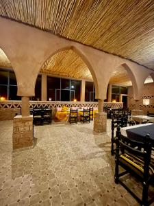 a large room with tables and chairs in a building at Aladdin Desert Camp - Mhamid Erg Chigaga Escape in El Gouera +63 photos