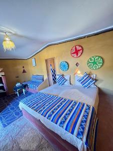 a bedroom with a large bed with colorful pillows at Aladdin Desert Camp - Mhamid Erg Chigaga Escape in El Gouera
