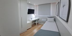 een kleine witte kamer met een bed en een bureau bij Riocentro, Projac, Parque Olímpico, apartamento completo com vaga! in Rio de Janeiro