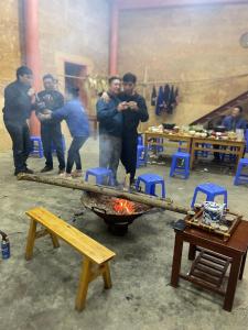 Un grupo de hombres de pie alrededor de una fogata en Mùa Pửi Lô lô homestay, en Mèo Vạc