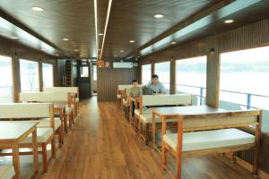 Trinetra Boat House - Dormitory في Honāvar: رجلان يجلسان على طاولات في عربة طعام في قطار