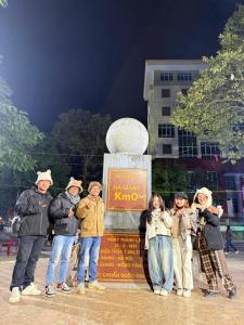 un grupo de personas de pie frente a una estatua en Mùa Pửi Lô lô homestay, en Mèo Vạc