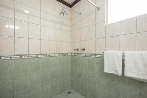 a bathroom with a shower with white towels at Casa del Sol - Poolside Villa in Quepos
