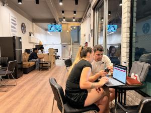 een man en een vrouw aan een tafel met een laptop bij Aura Hostel in Bangkok