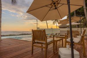 Una terraza de madera con mesas y sillas con sombrilla. en The rooftop Beach & club, en La Libertad