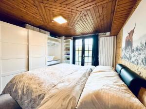 a large bed in a bedroom with a wooden ceiling at Résidence La Rose du Le Ours, 2 Zimmer Idyll am See in LʼAbbaye