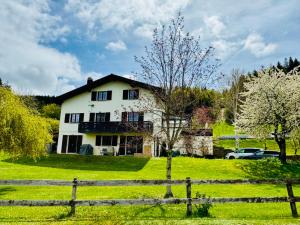 a white house in a field with a fence at Résidence La Rose du Le Ours, 2 Zimmer Idyll am See in LʼAbbaye